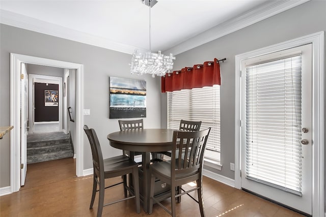 dining room featuring wood finished floors, baseboards, stairs, ornamental molding, and an inviting chandelier