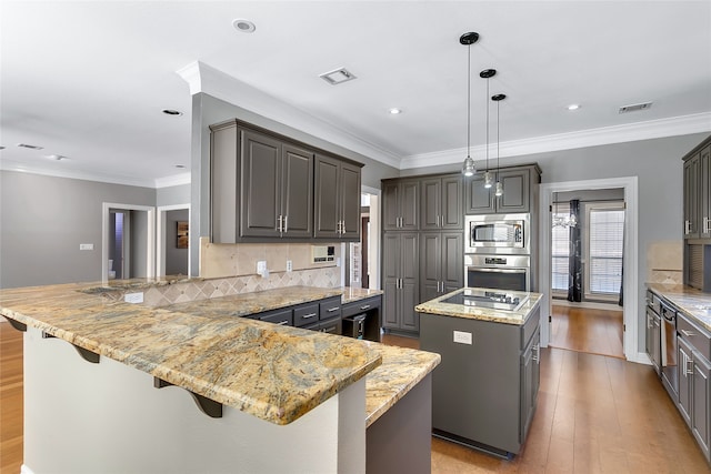 kitchen with kitchen peninsula, hanging light fixtures, stainless steel appliances, a kitchen island, and a kitchen breakfast bar