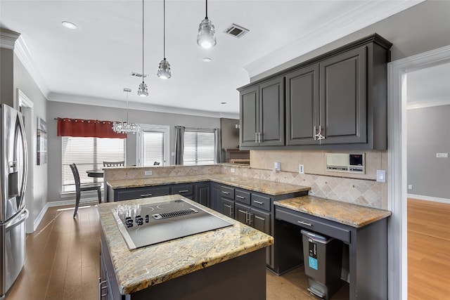 kitchen featuring a peninsula, black electric stovetop, plenty of natural light, and stainless steel fridge