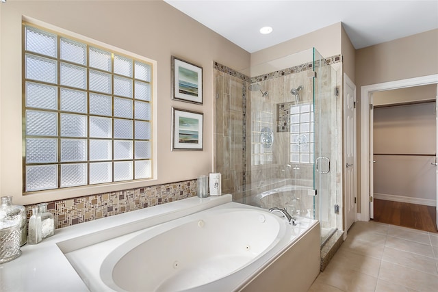 full bathroom featuring a jetted tub, tile patterned flooring, a shower stall, and a walk in closet