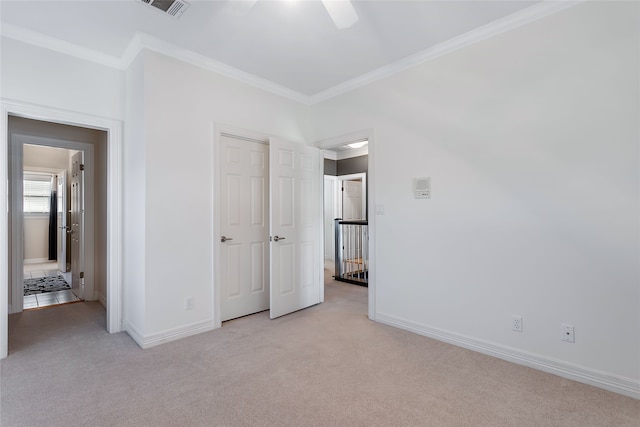 unfurnished bedroom featuring ceiling fan, light colored carpet, and crown molding