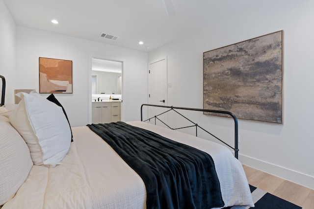 bedroom featuring ensuite bathroom and light hardwood / wood-style flooring