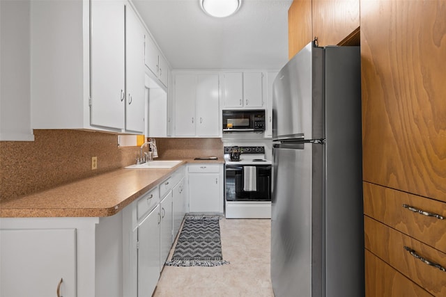 kitchen featuring electric range oven, sink, white cabinets, tasteful backsplash, and stainless steel fridge