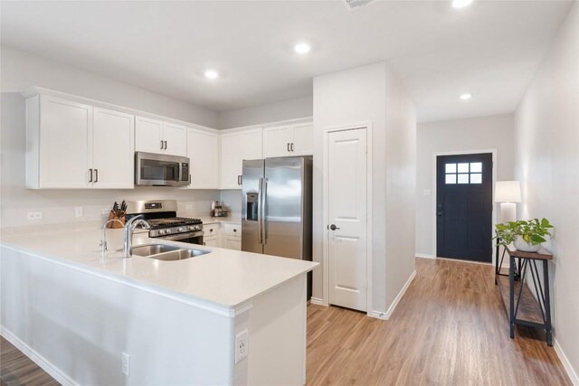 kitchen with white cabinets, stainless steel appliances, sink, and kitchen peninsula