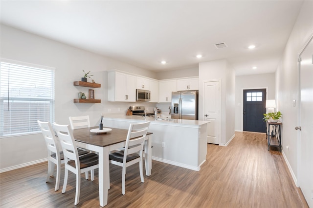 kitchen featuring kitchen peninsula, stainless steel appliances, light hardwood / wood-style flooring, and white cabinetry