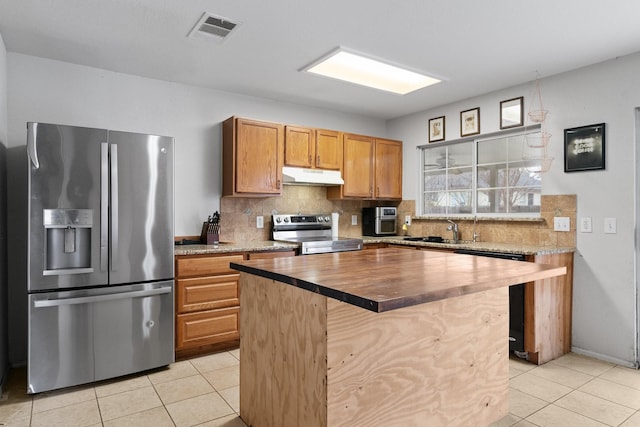 kitchen with stainless steel appliances, a center island, tasteful backsplash, and light tile patterned floors