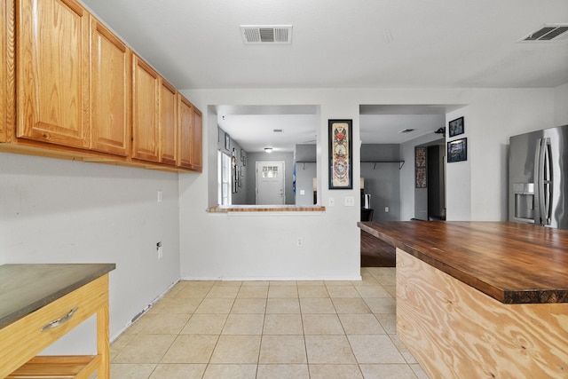 kitchen with stainless steel refrigerator with ice dispenser and light tile patterned floors