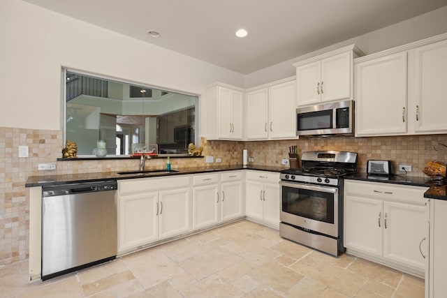 kitchen featuring stainless steel appliances, sink, white cabinets, dark stone countertops, and backsplash