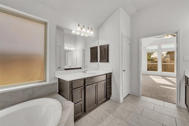 bathroom featuring tiled bath, vaulted ceiling, a notable chandelier, tile patterned floors, and vanity