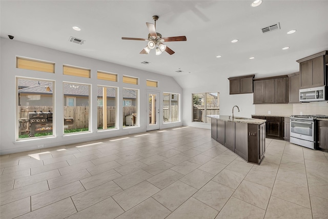 kitchen featuring stainless steel appliances, dark brown cabinetry, a wealth of natural light, and sink