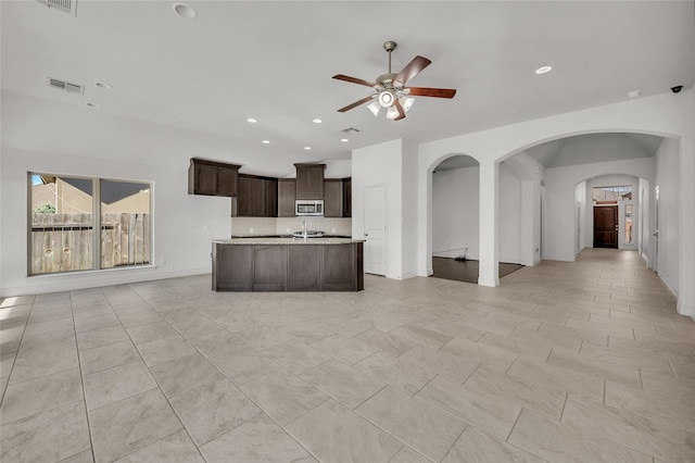 kitchen featuring a kitchen island with sink, light tile patterned floors, ceiling fan, sink, and dark brown cabinets