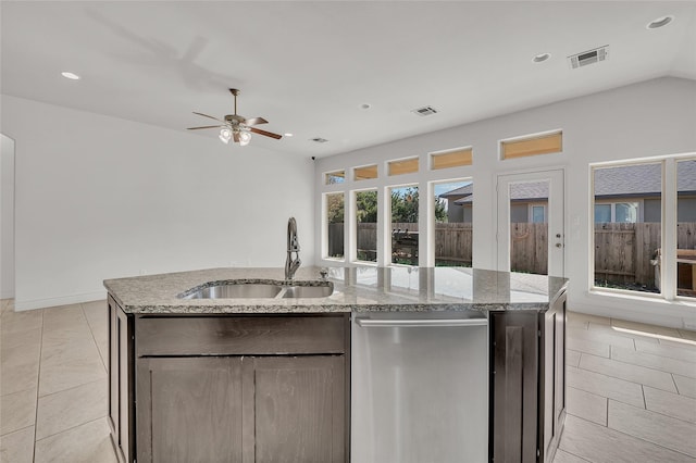 kitchen with light stone counters, light tile patterned floors, a kitchen island with sink, ceiling fan, and sink