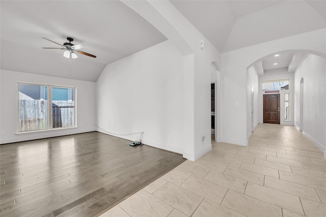 empty room with ceiling fan, light hardwood / wood-style flooring, vaulted ceiling, and a wealth of natural light