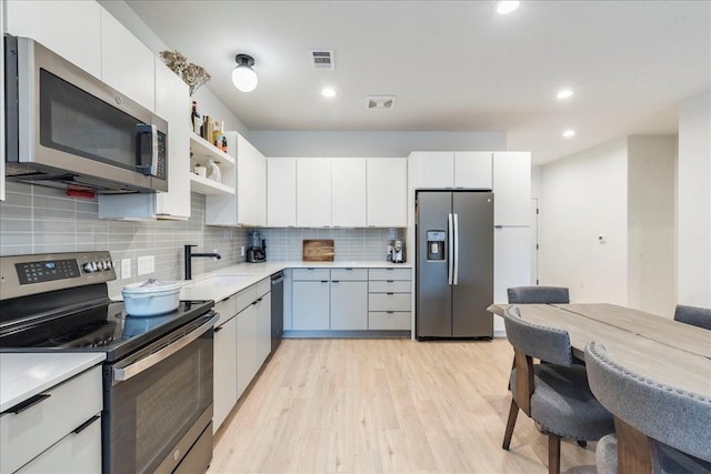 kitchen featuring appliances with stainless steel finishes, light hardwood / wood-style flooring, white cabinetry, and sink