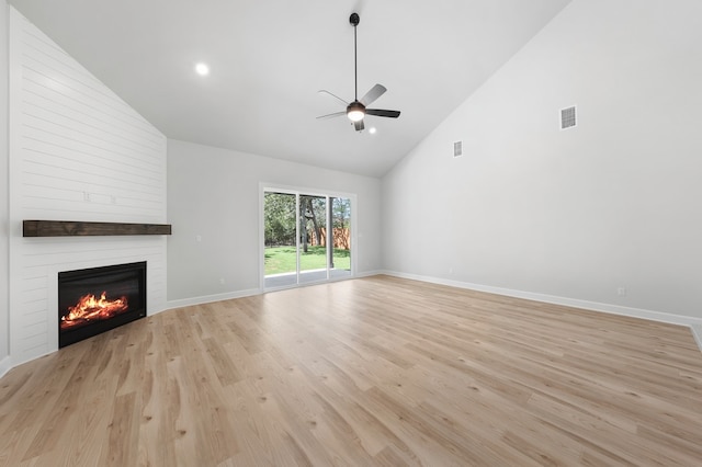 unfurnished living room with high vaulted ceiling, a large fireplace, ceiling fan, and light wood-type flooring