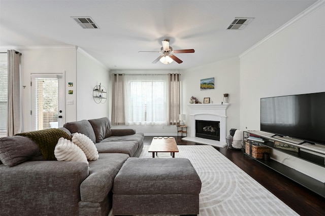 living room with ornamental molding, dark wood-type flooring, and ceiling fan