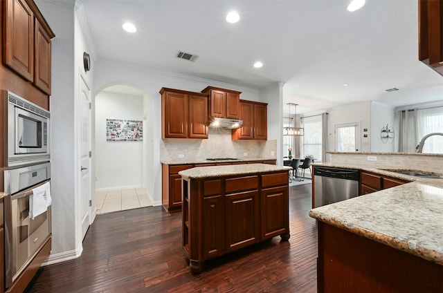 kitchen with appliances with stainless steel finishes, dark hardwood / wood-style floors, a center island, and sink