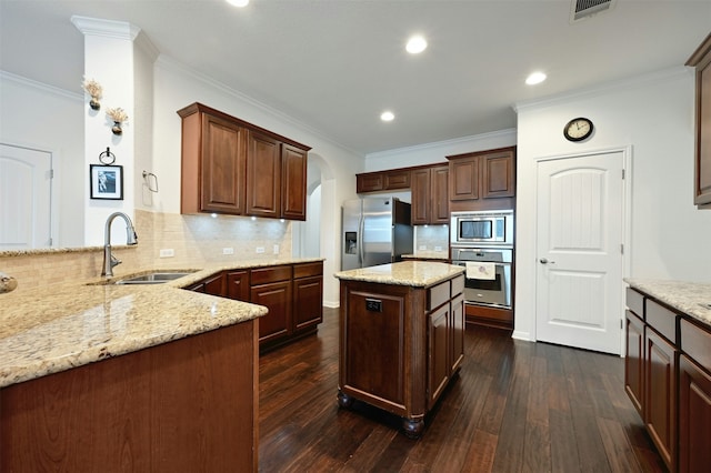 kitchen featuring stainless steel appliances, kitchen peninsula, light stone countertops, a kitchen island, and sink