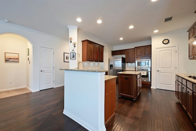 kitchen with a center island, tasteful backsplash, kitchen peninsula, crown molding, and appliances with stainless steel finishes