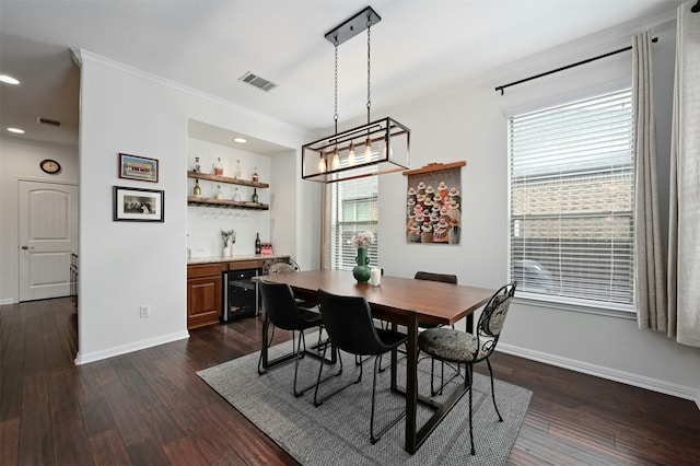 dining space featuring bar, beverage cooler, crown molding, and dark hardwood / wood-style flooring