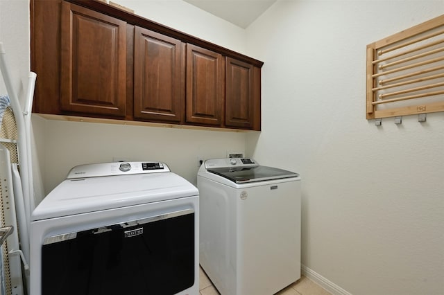 clothes washing area with independent washer and dryer, cabinets, and light tile patterned floors