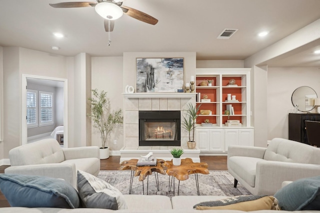 living room with a tile fireplace, ceiling fan, and wood-type flooring