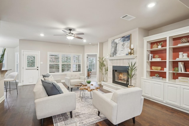 living room with a tiled fireplace, ceiling fan, and dark hardwood / wood-style floors