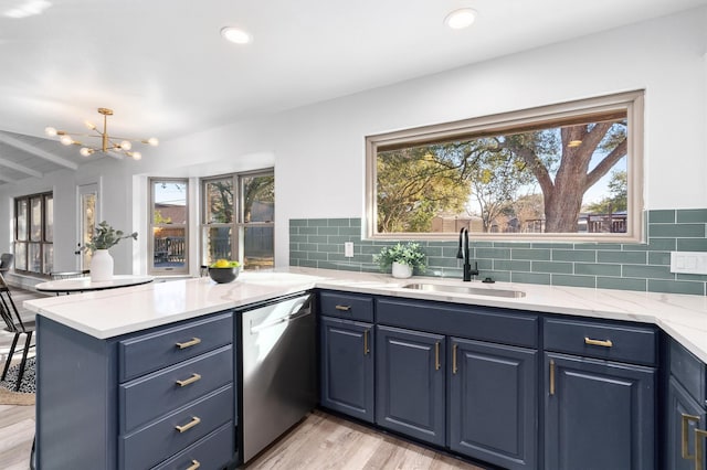 kitchen featuring dishwasher, light wood-type flooring, blue cabinetry, kitchen peninsula, and sink