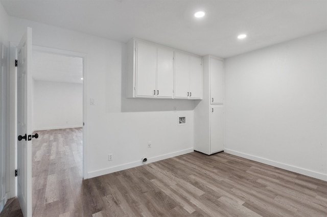 clothes washing area with hookup for a washing machine, cabinets, and light hardwood / wood-style floors