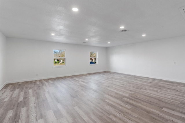 empty room with a textured ceiling and light hardwood / wood-style floors