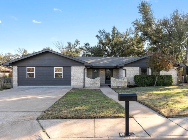 ranch-style home featuring stone siding, a front lawn, and driveway