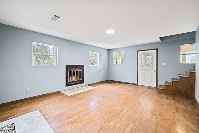 unfurnished living room featuring a healthy amount of sunlight and light hardwood / wood-style flooring