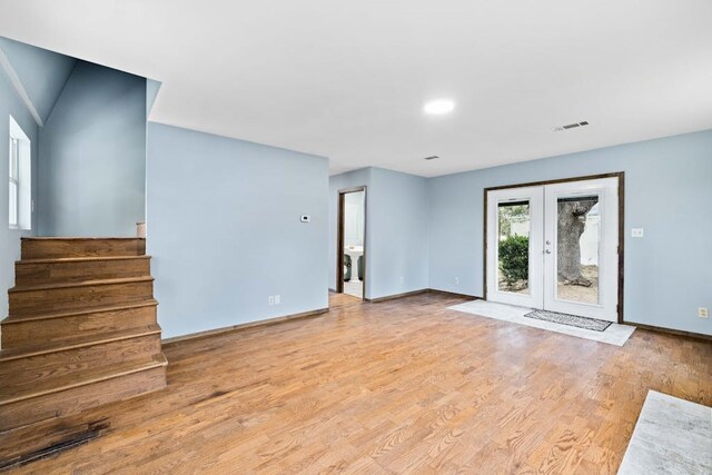 unfurnished living room featuring light hardwood / wood-style floors and french doors