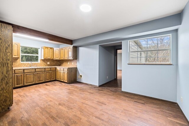 kitchen featuring sink, hardwood / wood-style floors, backsplash, and beam ceiling