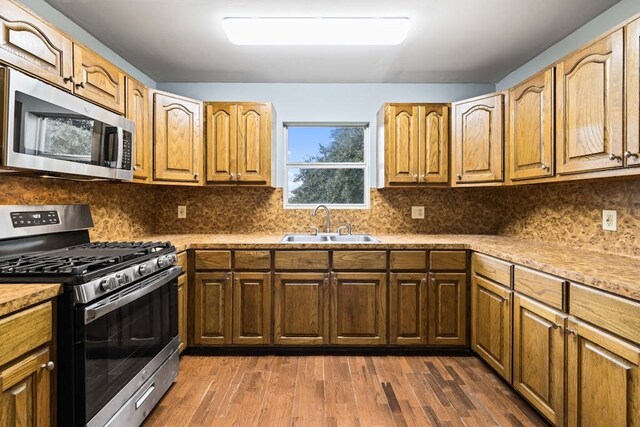 kitchen with sink, dark hardwood / wood-style floors, tasteful backsplash, and appliances with stainless steel finishes