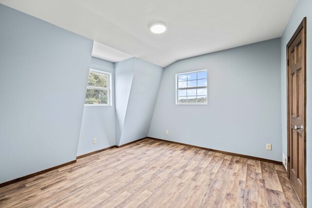 unfurnished bedroom with lofted ceiling and light hardwood / wood-style flooring