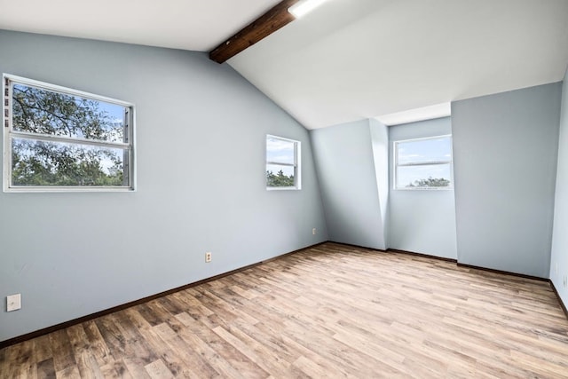 additional living space featuring light wood-type flooring and lofted ceiling with beams