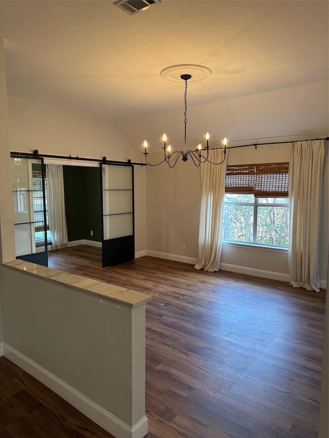 unfurnished room with a notable chandelier, dark wood-type flooring, vaulted ceiling, and a barn door