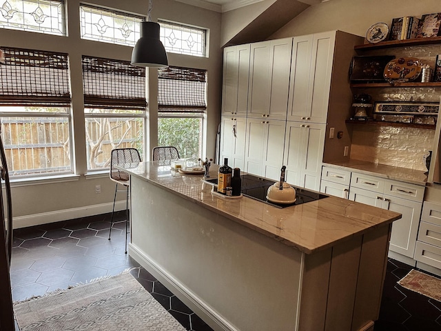 kitchen with light stone countertops, white cabinets, pendant lighting, and a healthy amount of sunlight