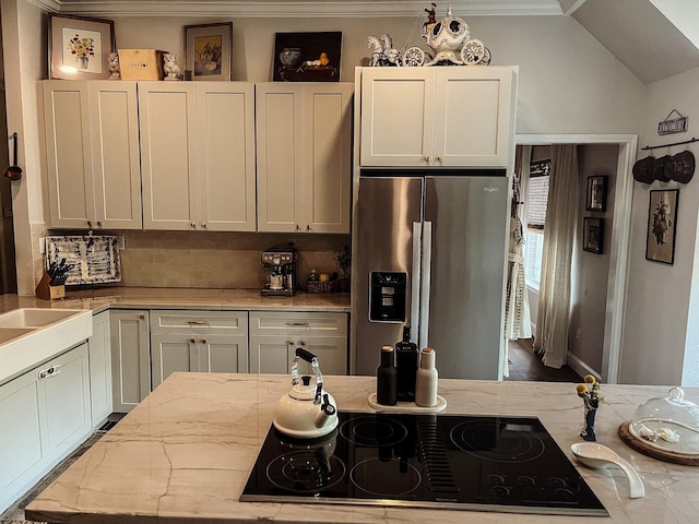 kitchen featuring light stone counters, white cabinets, stainless steel fridge with ice dispenser, and black electric cooktop