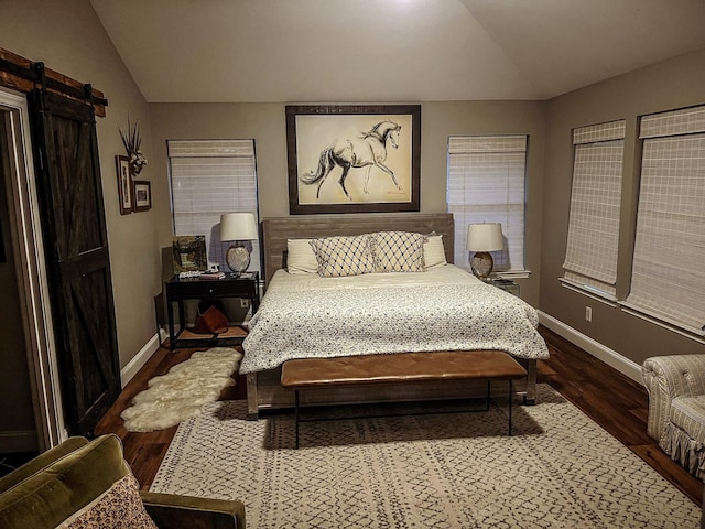 bedroom featuring lofted ceiling, hardwood / wood-style floors, and a barn door