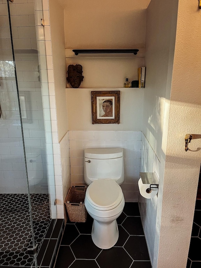 bathroom featuring toilet, an enclosed shower, tile patterned floors, and tile walls