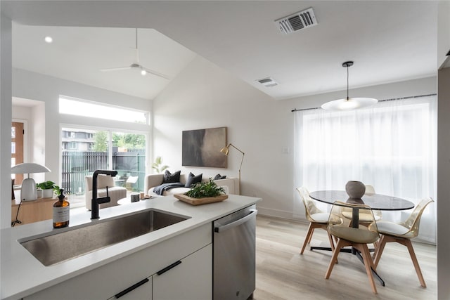 kitchen with stainless steel dishwasher, vaulted ceiling, hanging light fixtures, white cabinetry, and sink