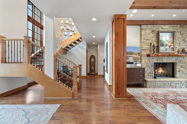 entrance foyer with beam ceiling, a chandelier, hardwood / wood-style floors, and a fireplace