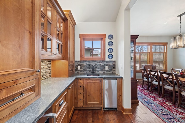 kitchen featuring pendant lighting, decorative backsplash, an inviting chandelier, dark hardwood / wood-style flooring, and sink