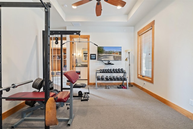 workout room featuring carpet floors, ceiling fan, and a tray ceiling