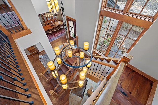 staircase featuring a high ceiling, an inviting chandelier, and wood-type flooring