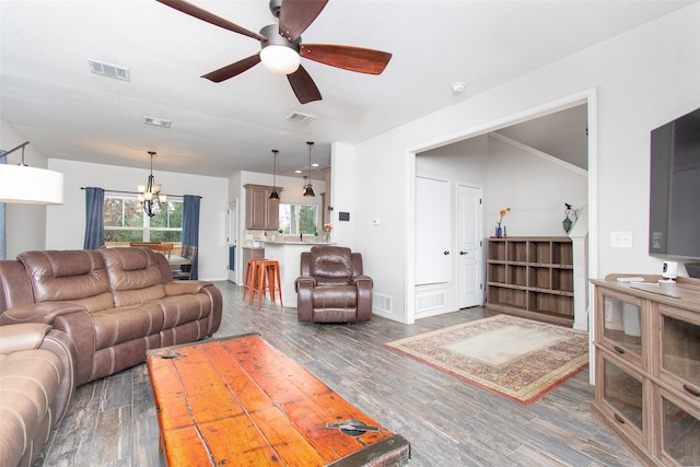 living room featuring dark hardwood / wood-style flooring and ceiling fan with notable chandelier