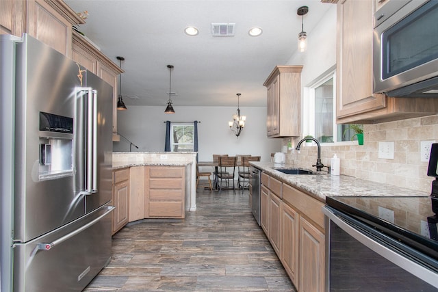 kitchen featuring light stone countertops, decorative light fixtures, sink, and appliances with stainless steel finishes