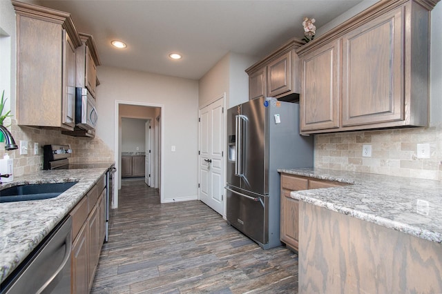 kitchen featuring stainless steel appliances, decorative backsplash, sink, and light stone counters